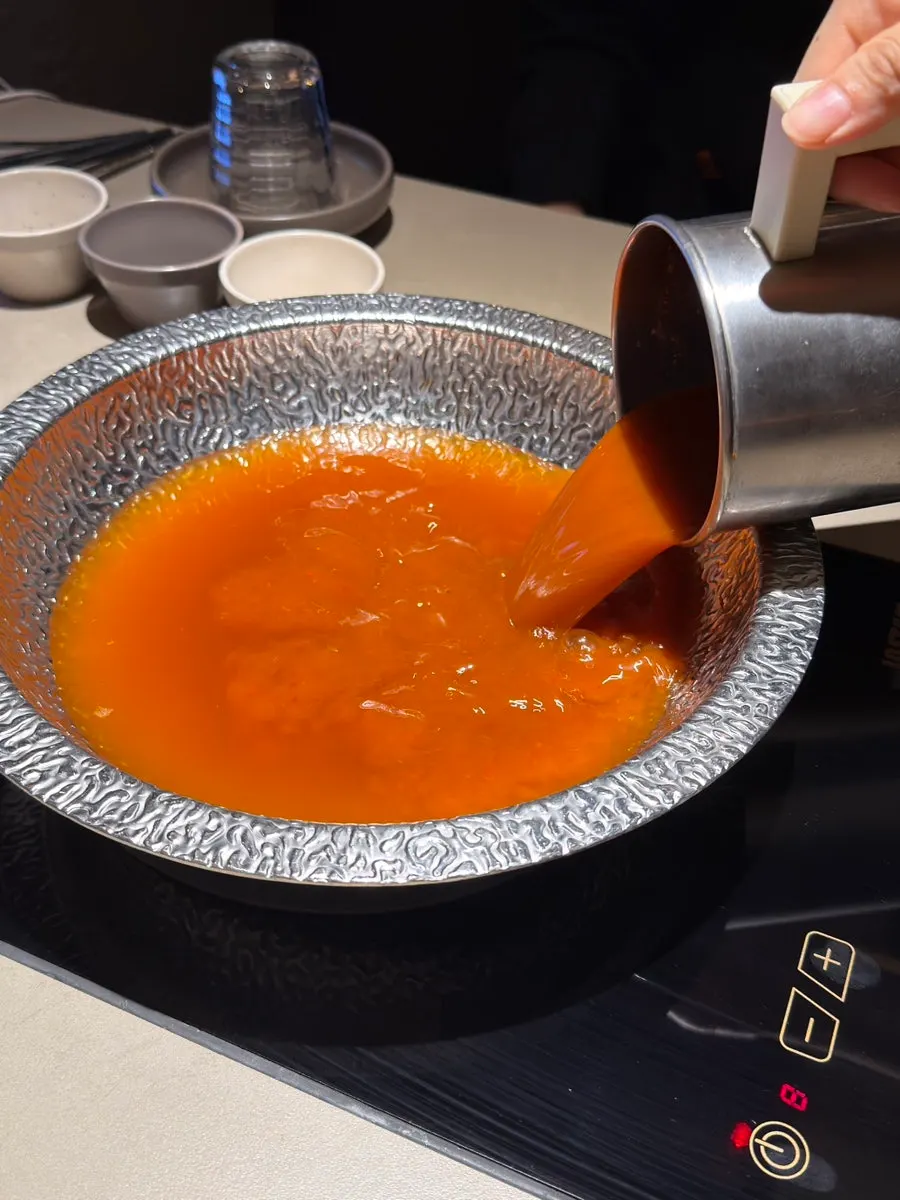 Pot of spicy mushroom broth and shabu-shabu ingredients set up