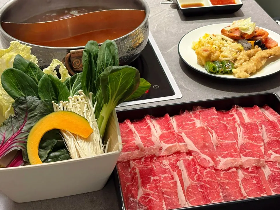 Table with salad bar plates and shabu-shabu pot