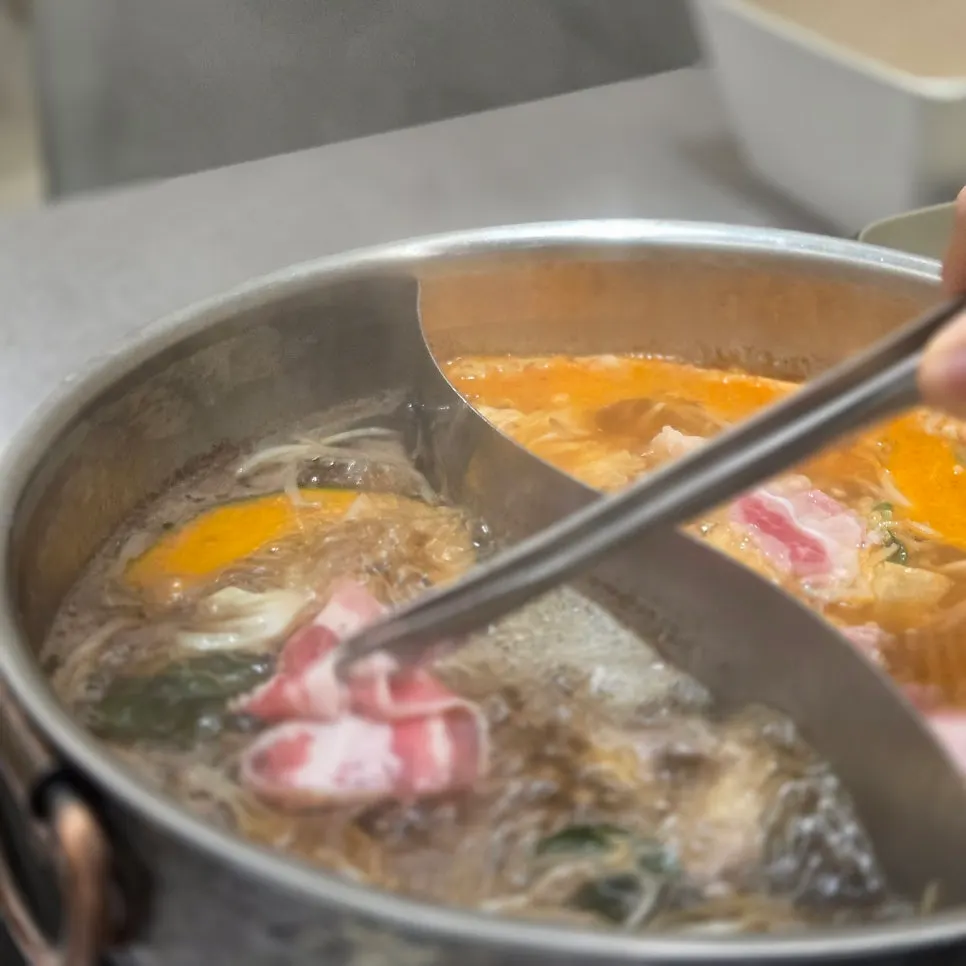 Split broth pot simmering with vegetables and beef