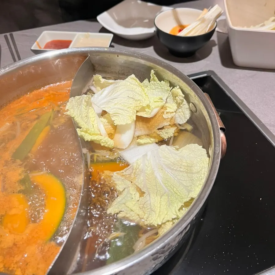 A pot of half-and-half broth loaded with vegetables and mushrooms