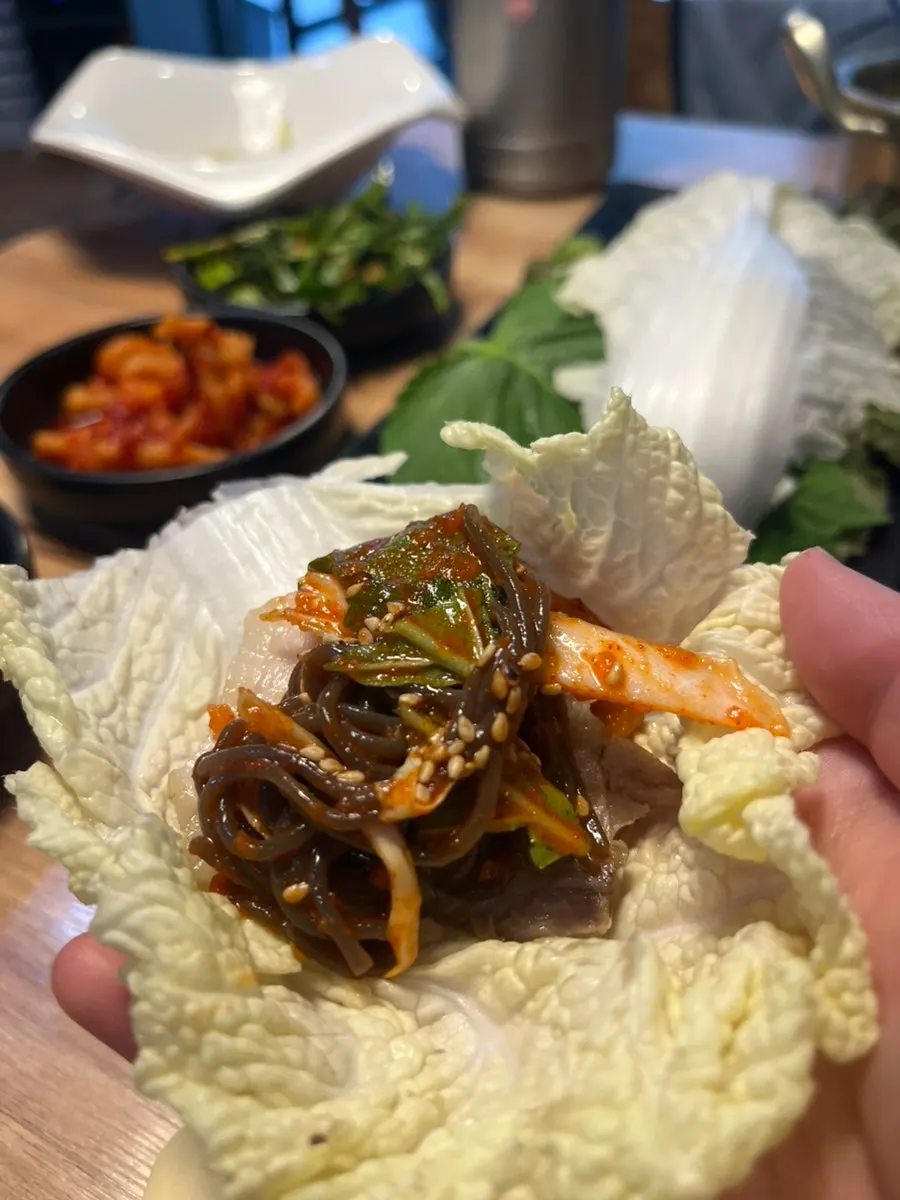 보쌈을 막국수 면에 돌돌 말아 먹는 모습