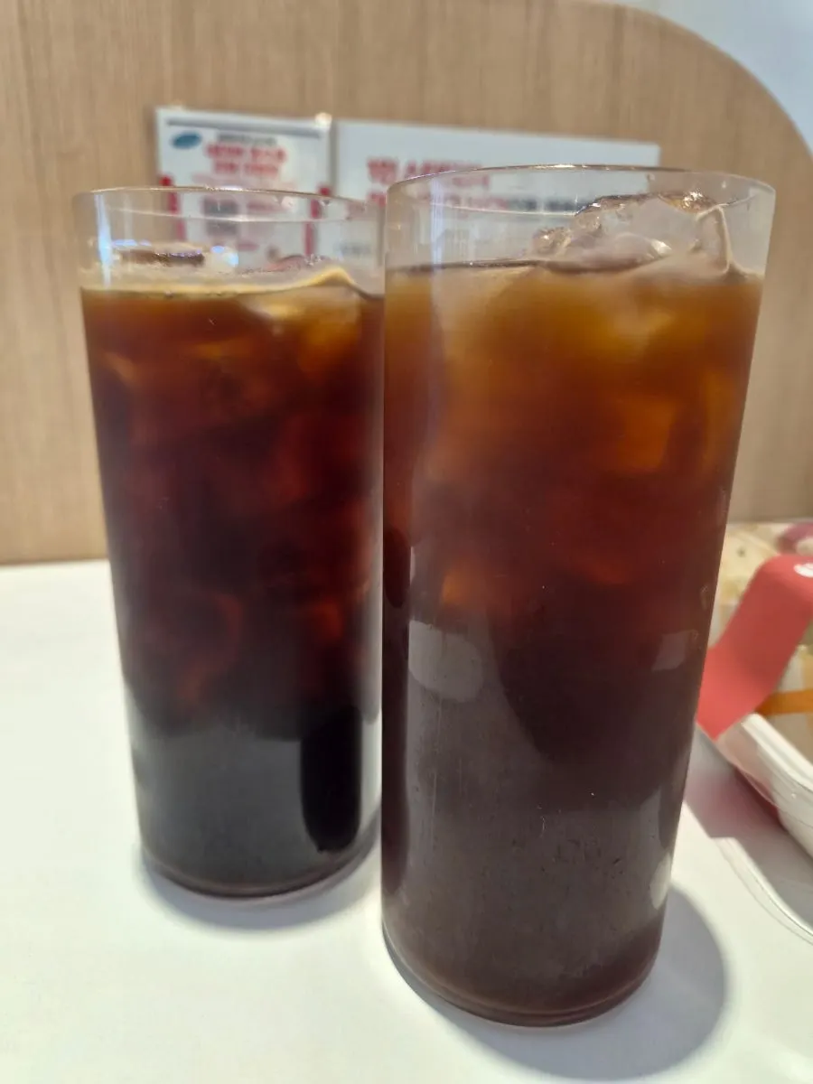 Two coffees set up alongside a chicken sandwich