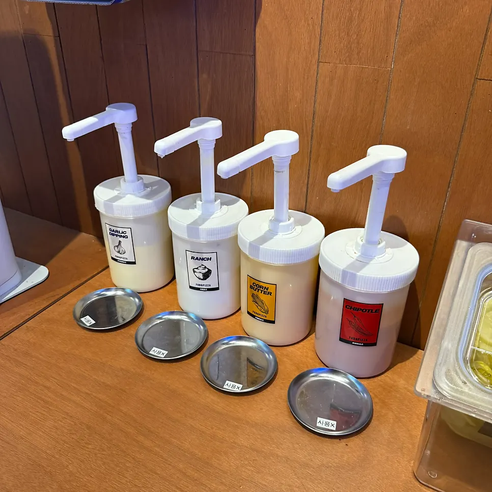 Pickles, garlic sauce, and parmesan cheese at the self-serve bar