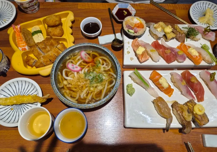A table spread of sushi and udon together at Shirokuma