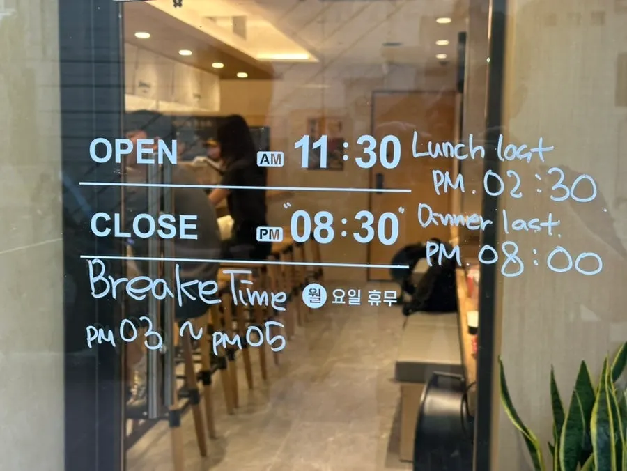 Sign at Shomendo noting free noodle refills and business hours