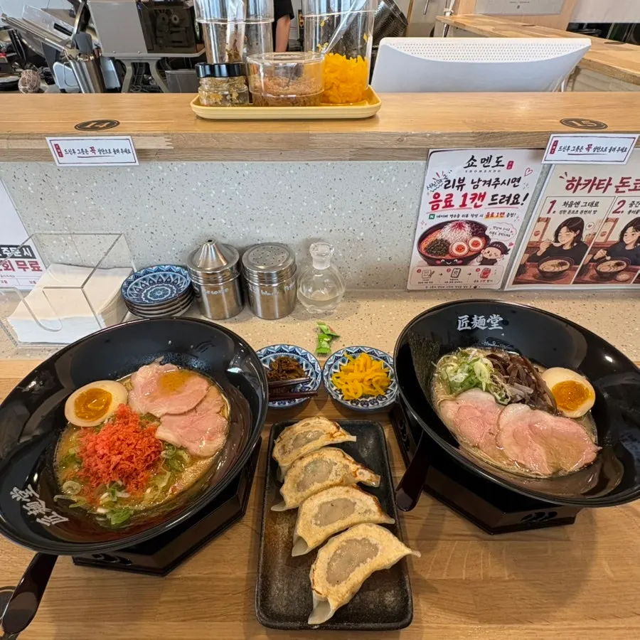 Table set with two bowls of ramen and gyoza