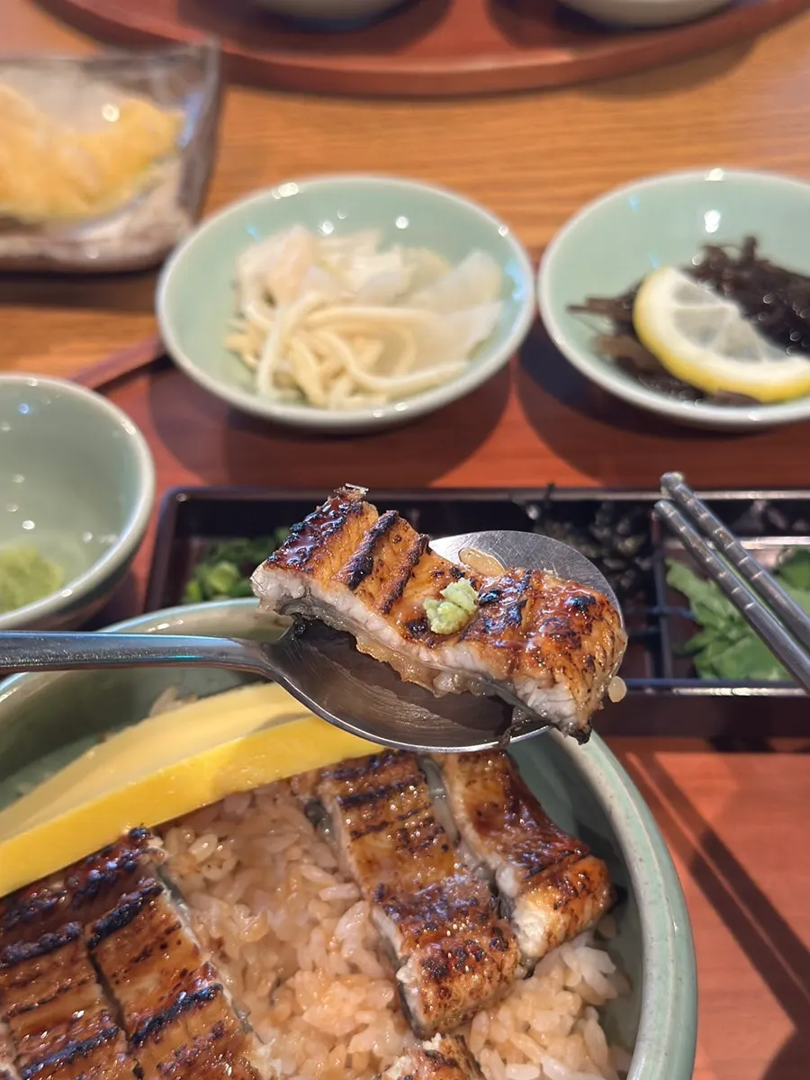 A bite of eel rice bowl topped with wasabi