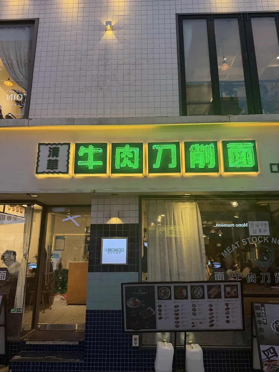 Green neon sign reading beef knife-cut noodles