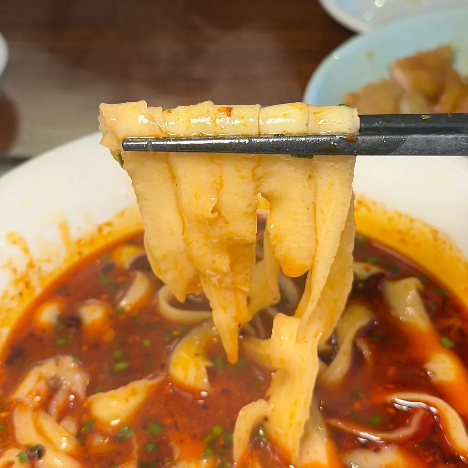 Thick knife-cut noodles lifted with chopsticks