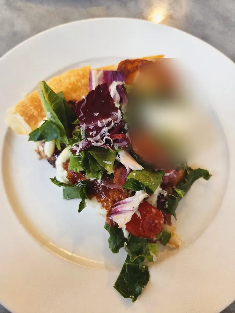 A slice of pizza topped with ricotta cheese and salad