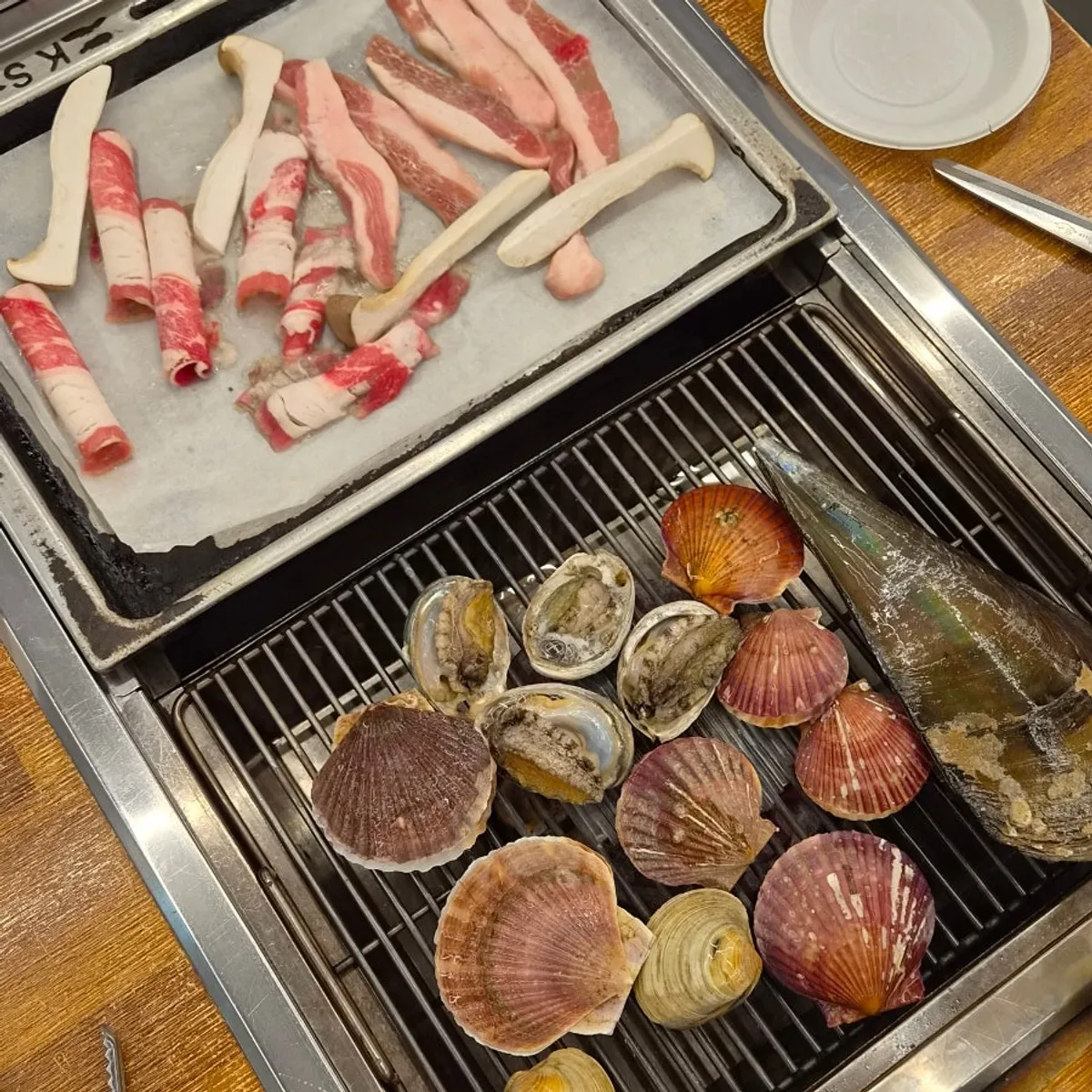 Shellfish and meat cooking together on the grill