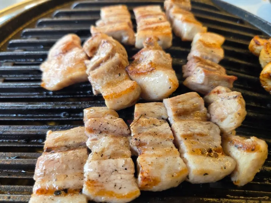 Grilling pork belly on the left and eel on the right at the same time