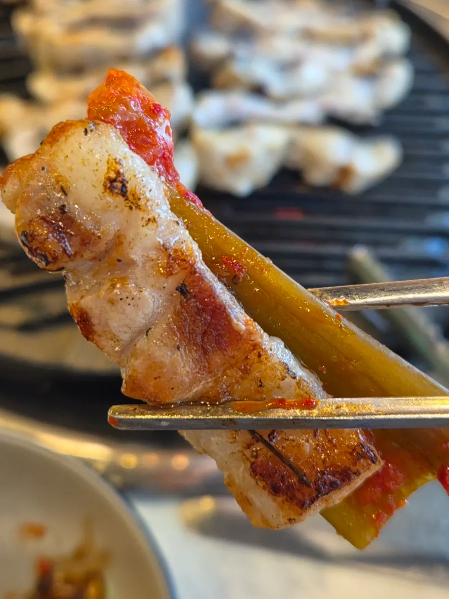 Fresh eel placed in the center of the grill with cooked eel set aside