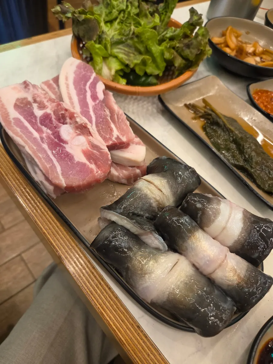 불판에 산처럼 쌓아 올린 장어와 삼겹살