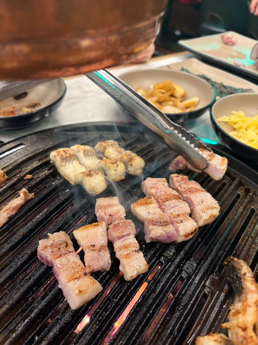 Whole pork belly placed on the grill next to the eel