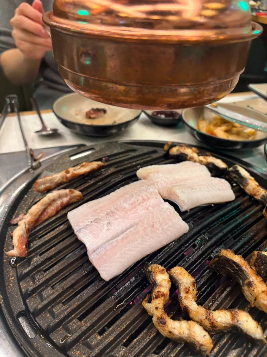 Grill with whole pork belly and duck neck alternating on it