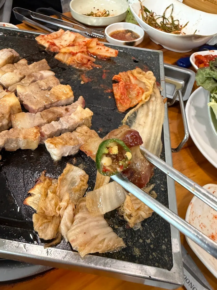 Meat, aged kimchi, and doenjang grilling together on the pan