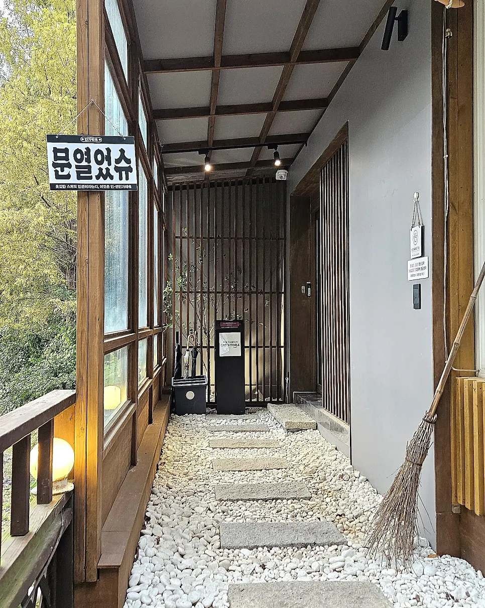 우드톤 기둥과 자갈 디딤돌이 있는 한옥풍 입구
