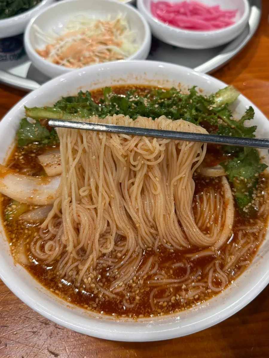 Signature bibim guksu topped with chicory and kimchi