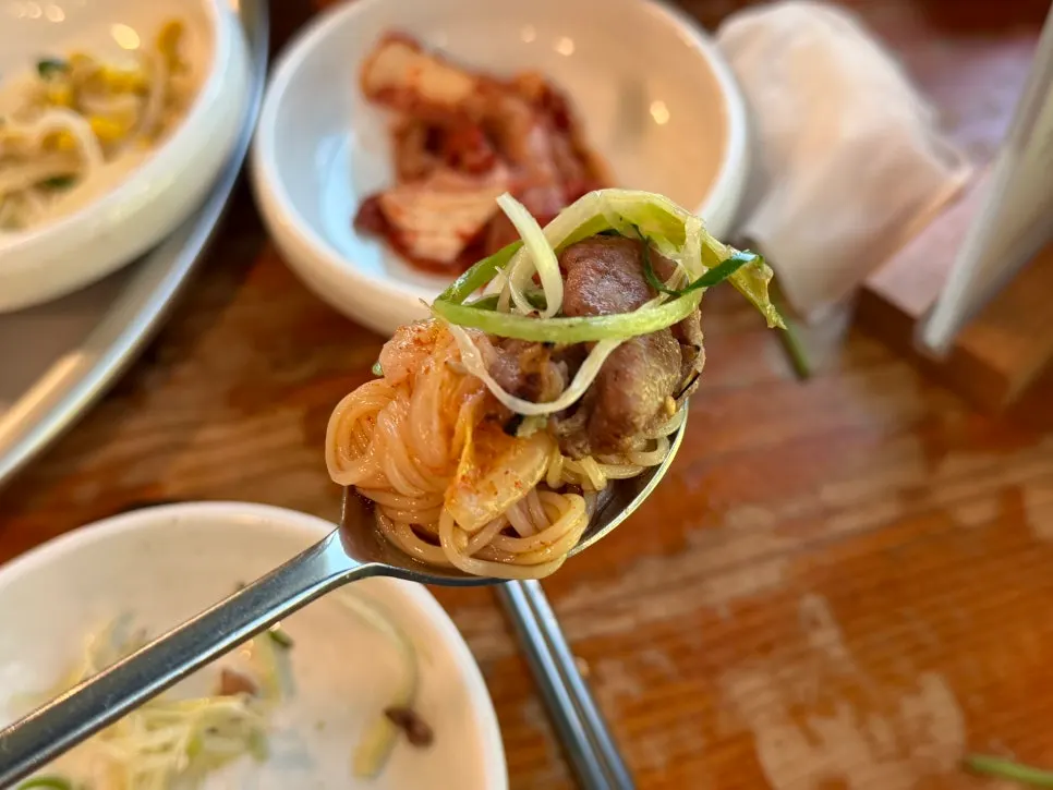 A bite of bulgogi rolled up with bibim noodles