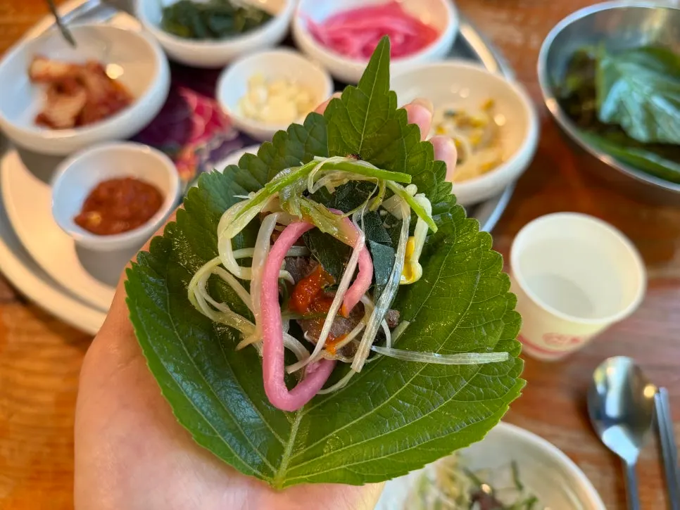 A wrap of bulgogi and side dishes in a lettuce leaf