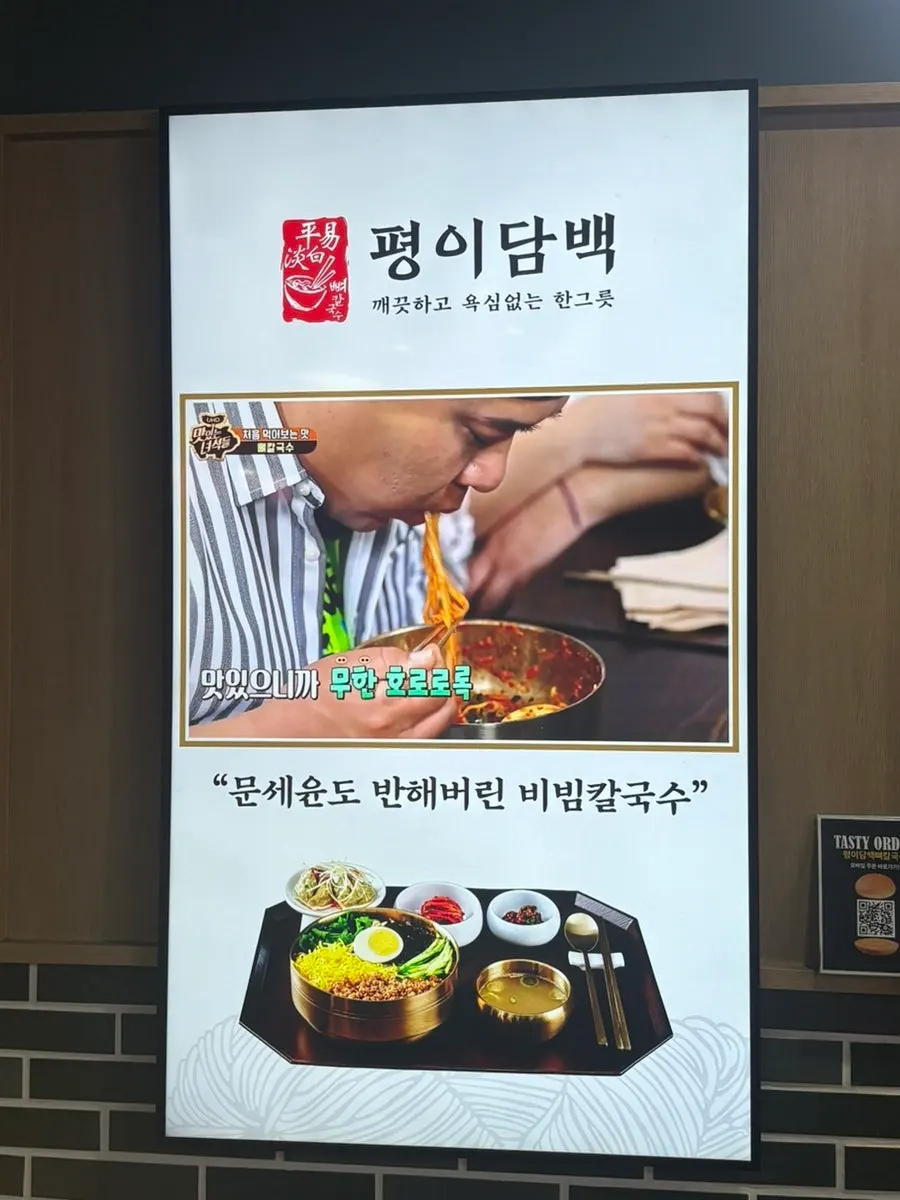 Entrance of Pyeongi Dambaek Bone Kalguksu with a sign noting its TV feature