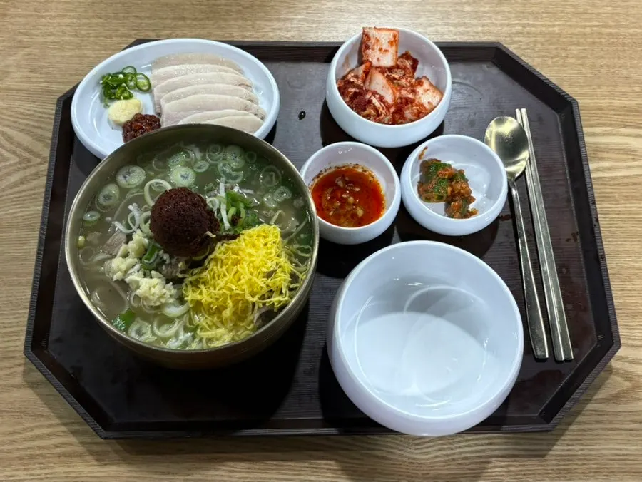 Table spread with spicy bone kalguksu and pork jowl suyuk served together