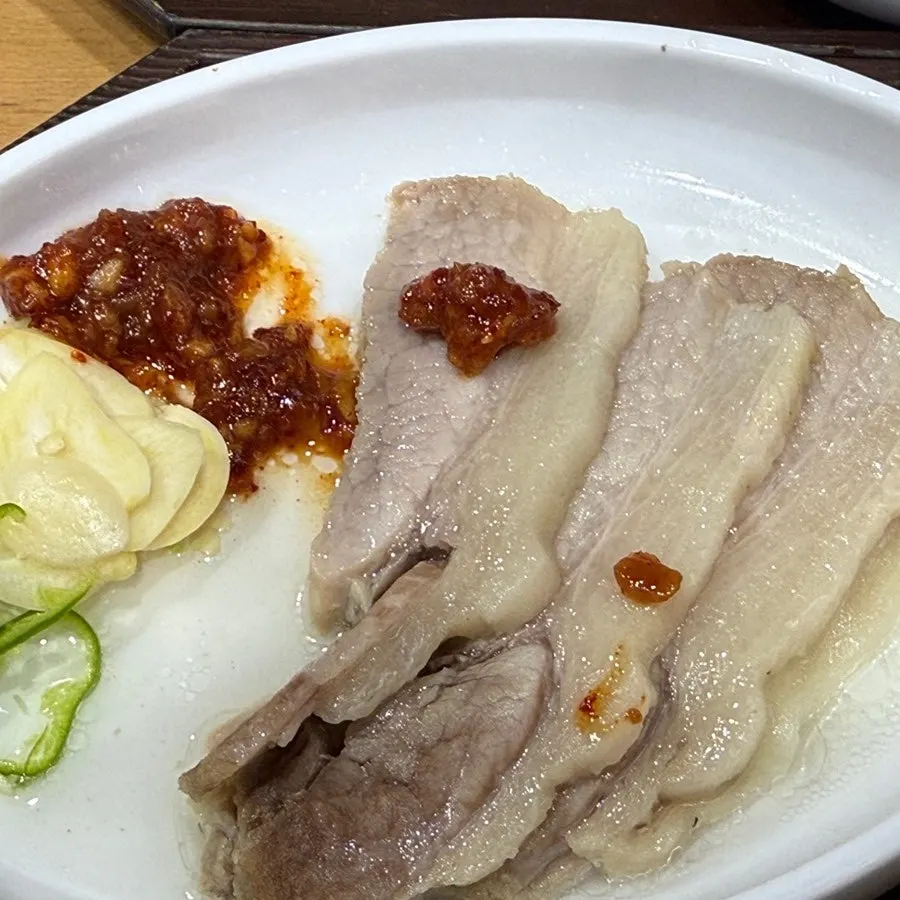 A piece of pork jowl suyuk topped with seasoning sauce
