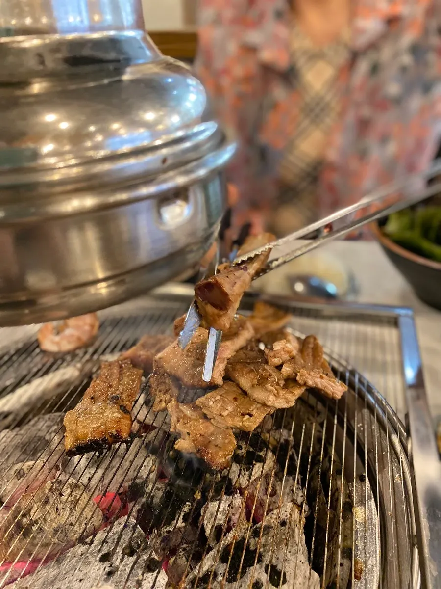 쌈 채소에 올린 숯불 고기 한 쌈