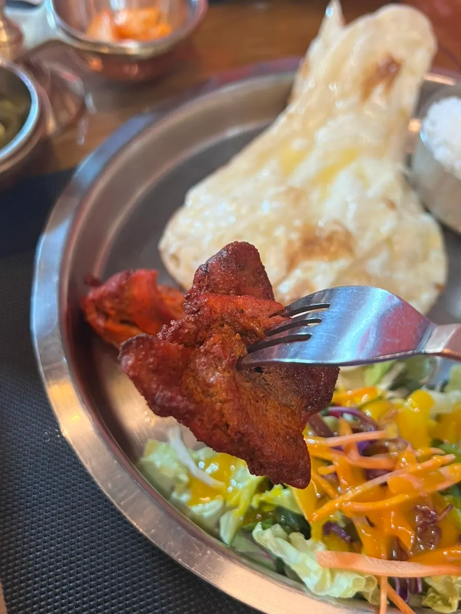 Butter naan dipped into chicken makhani