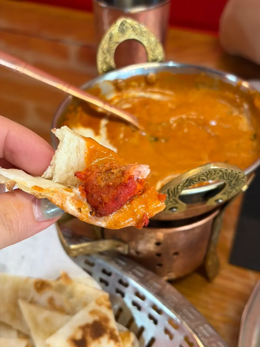 Dipping tandoori chicken into butter chicken curry