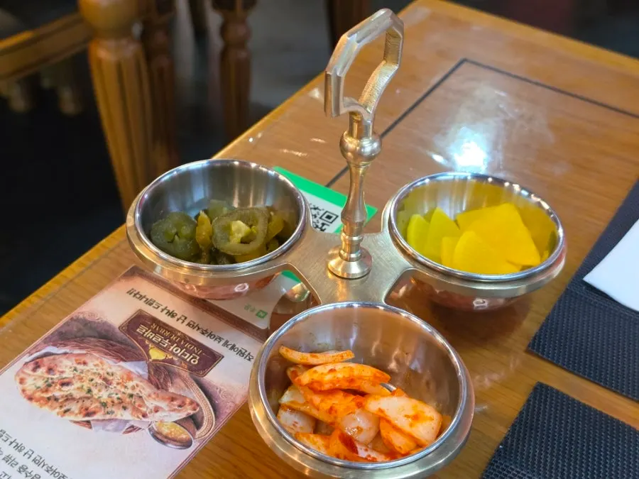 Three-compartment tray with pickles, seasoned onion and pickled radish