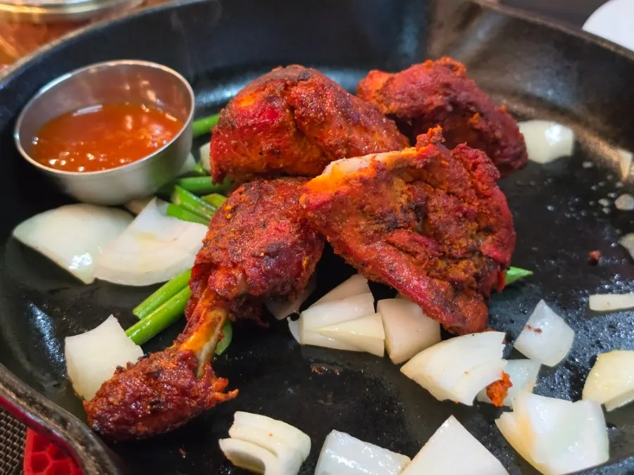 Tandoori chicken half served on a red sizzling pan