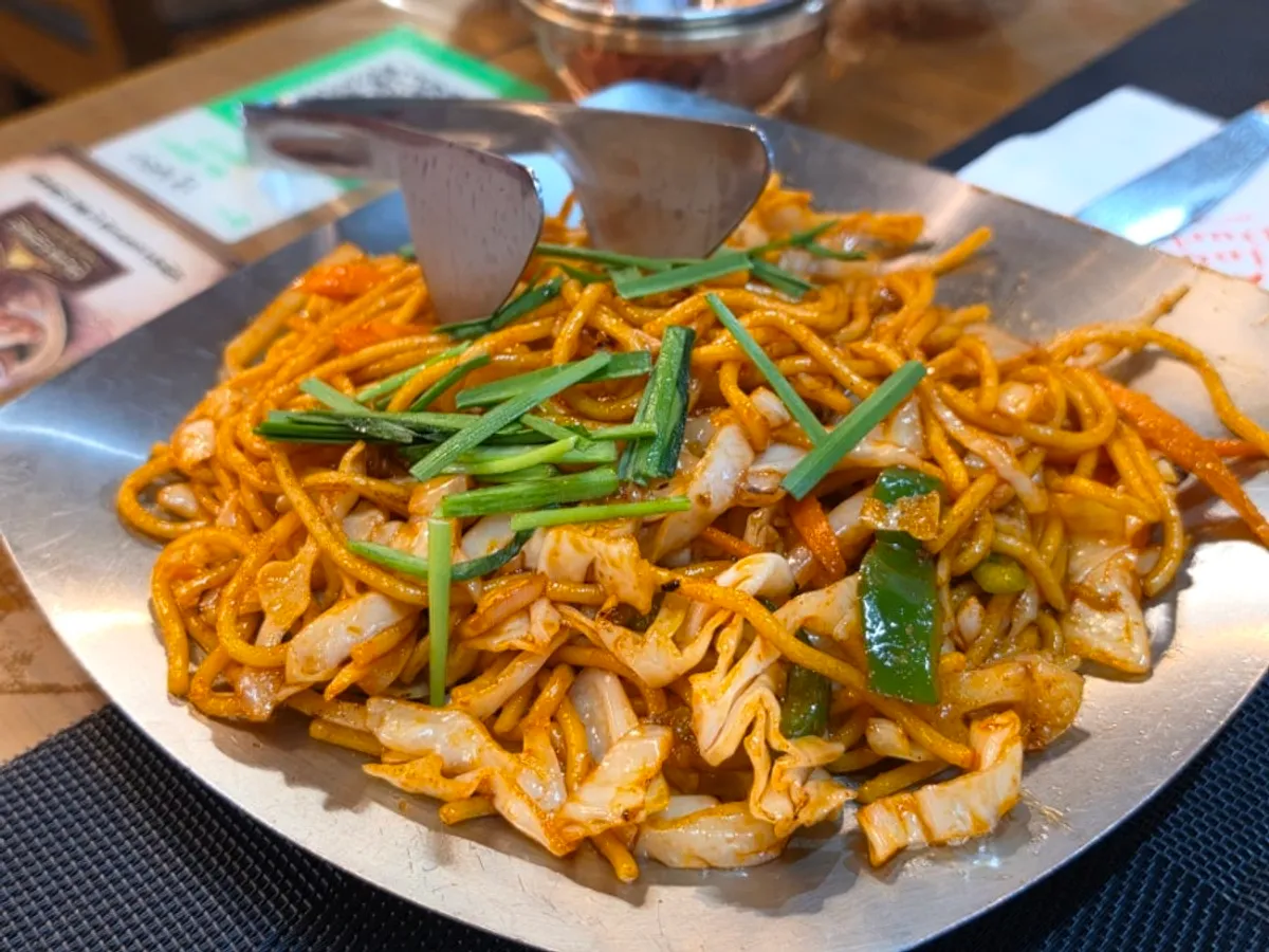 A plate of vegetable fried noodles coated in red seasoning