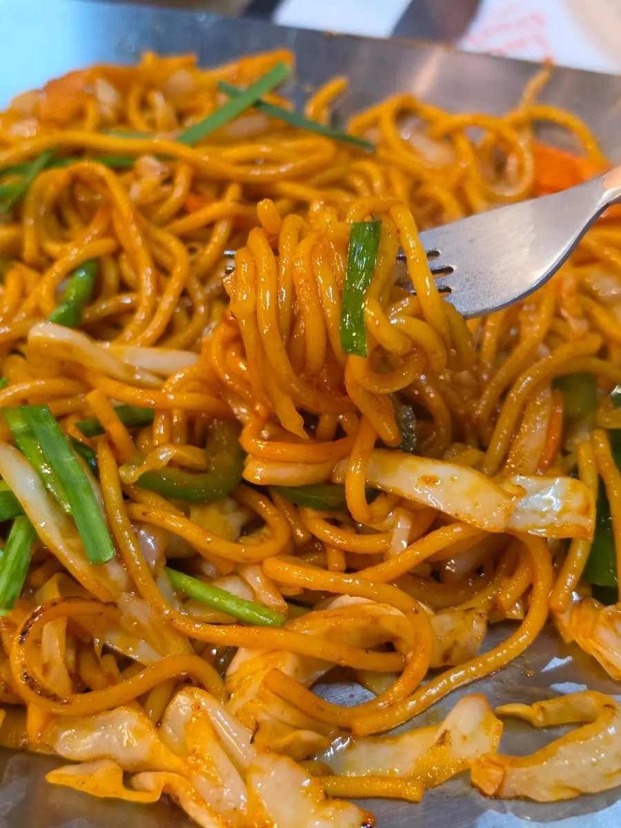 Vegetable fried noodles lifted up with chopsticks