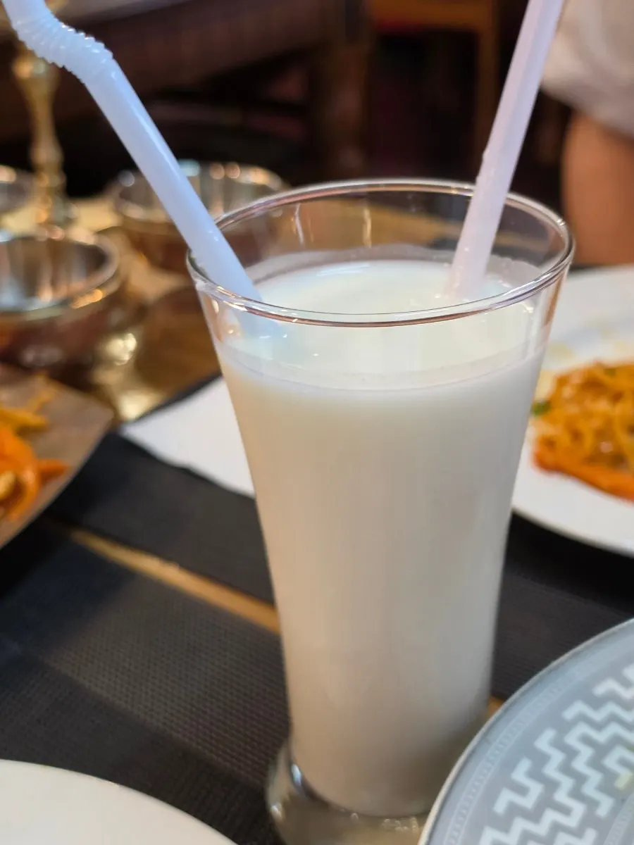 A glass of lassi paired with the spicy fried noodles