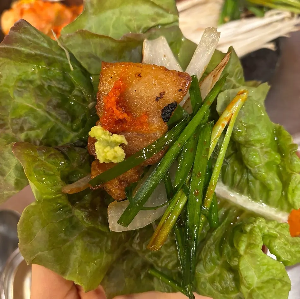 A bite of meat and grilled vegetables piled on wild garlic leaves