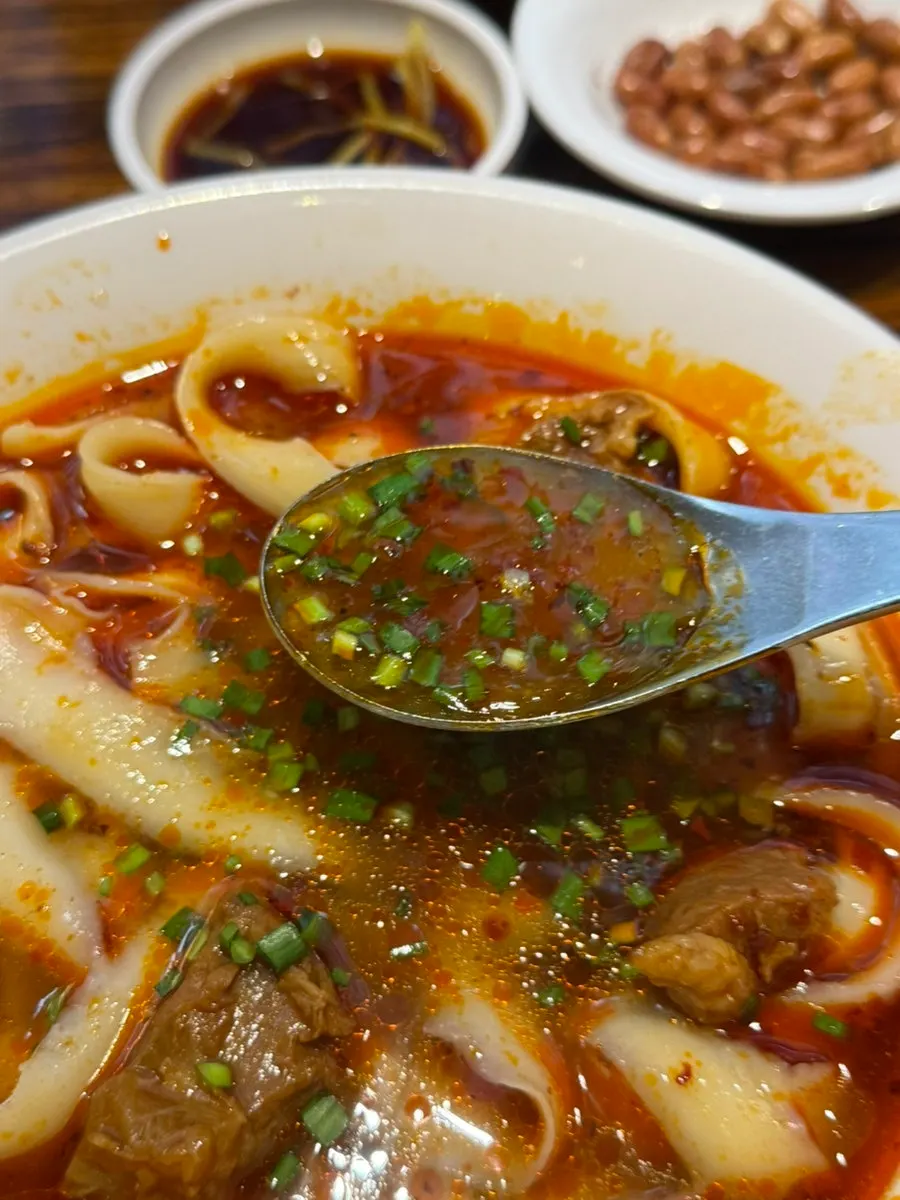 Mala-style beef noodle broth with chives