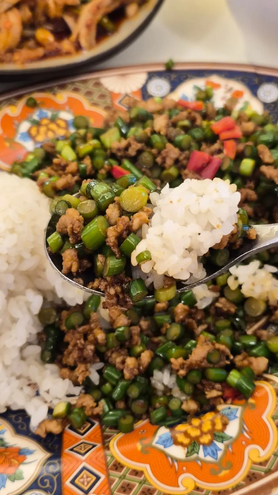 A spoonful of the rice bowl with garlic scapes and pork