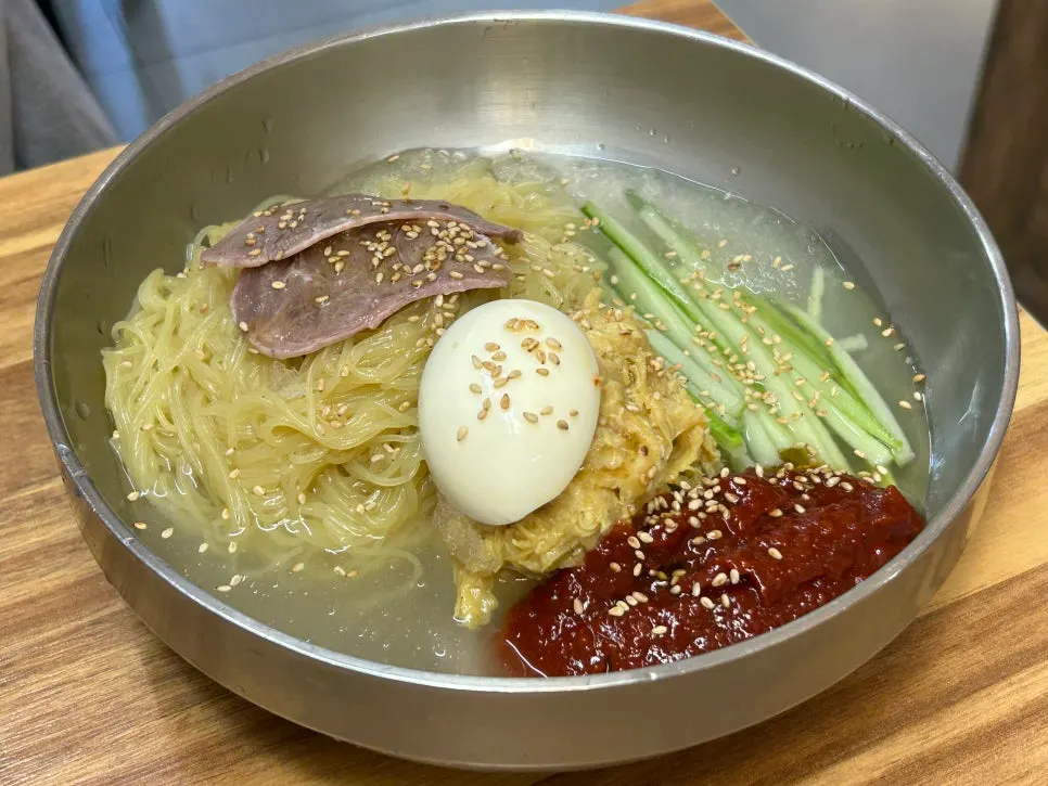A bowl of chogye bibim naengmyeon topped with garnish