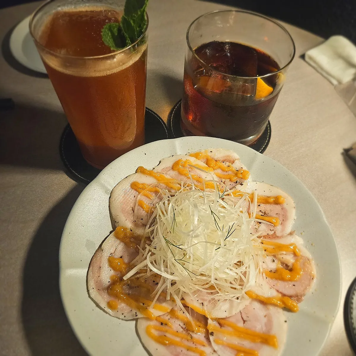 흑돼지 카르파치오와 칵테일 두 잔이 놓인 테이블
