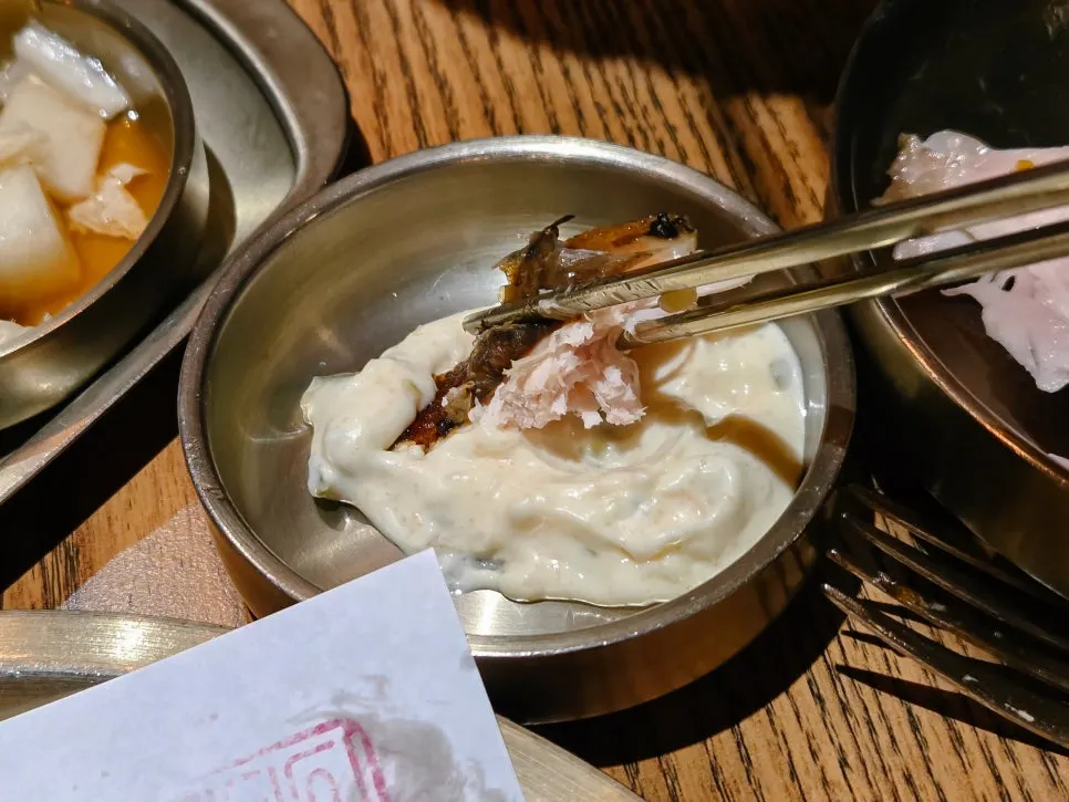 A piece of wood-fired chicken topped with seed jeotgal