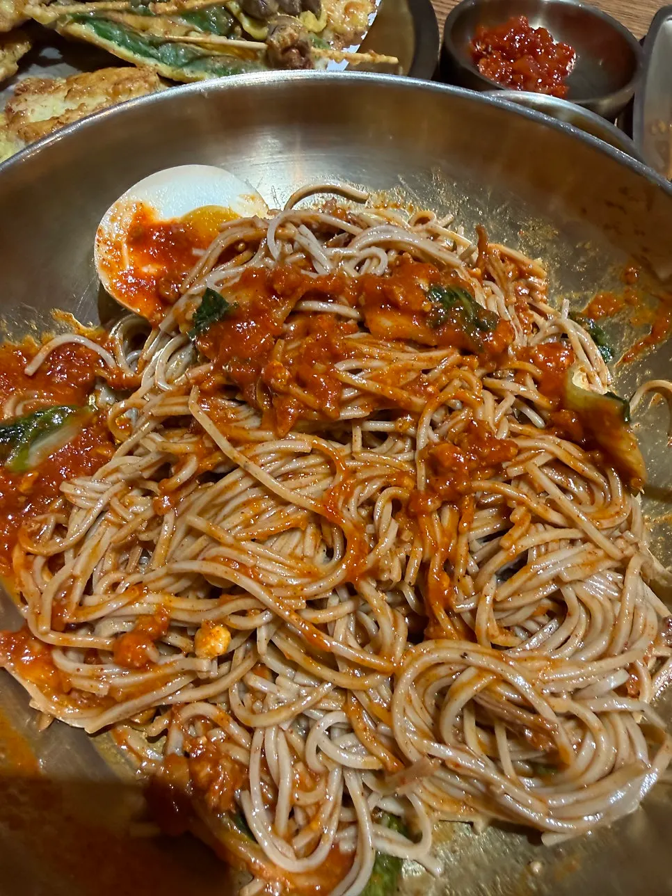 Lifting a bite of makguksu noodles with chopsticks