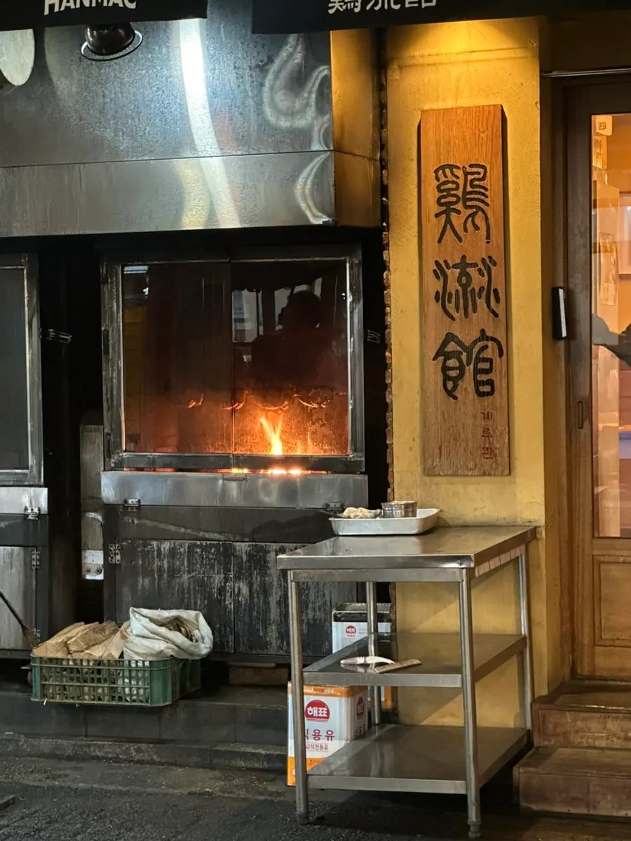 Wood-fired grilling over an open flame in front of the restaurant