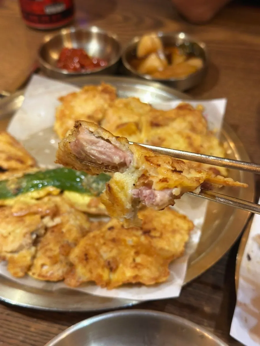Chopsticks picking up a piece of assorted chicken jeon