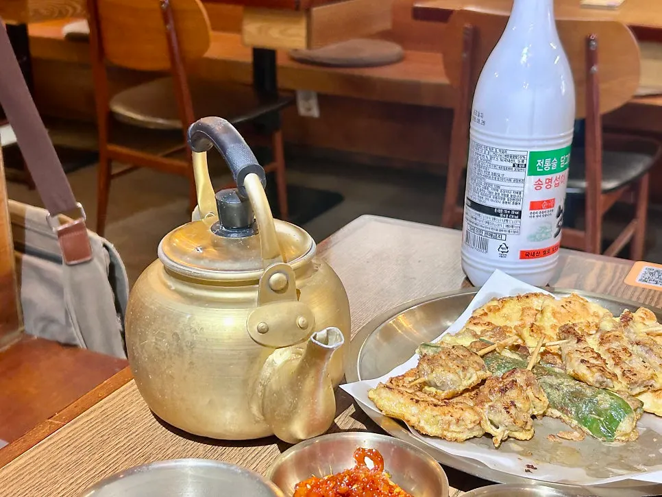잔에 따른 막걸리와 장작구이 상차림