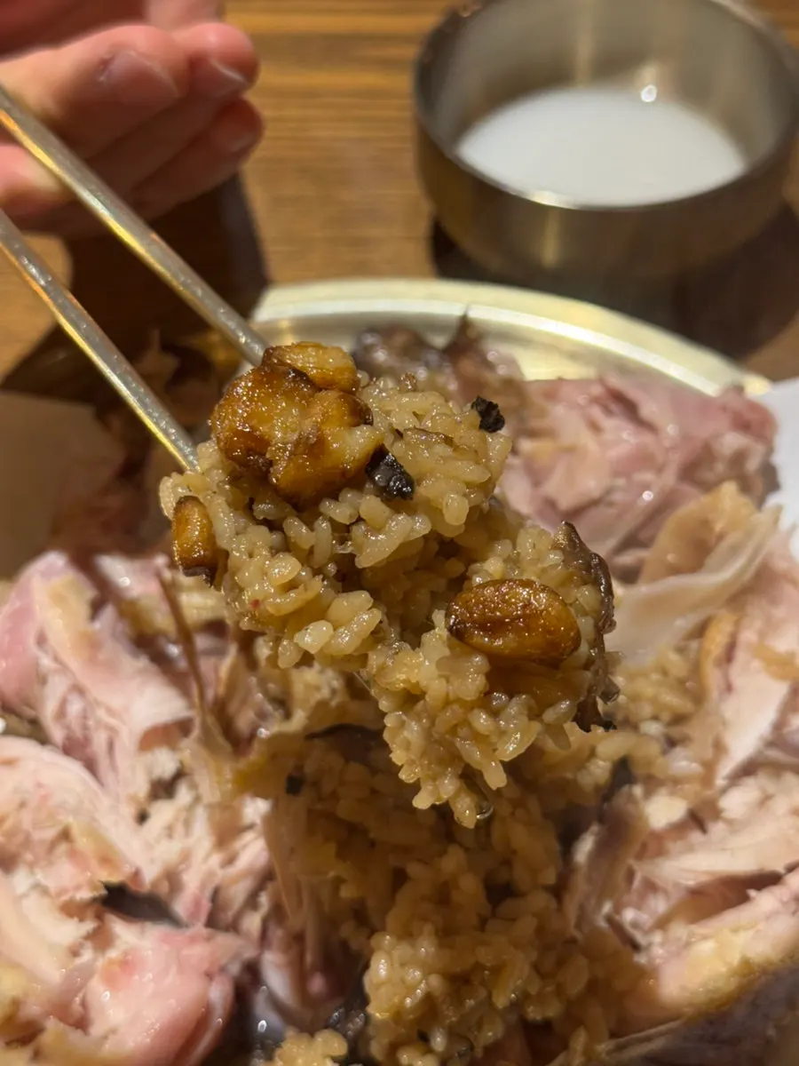 A bite of chicken and glutinous rice topped with kimchi