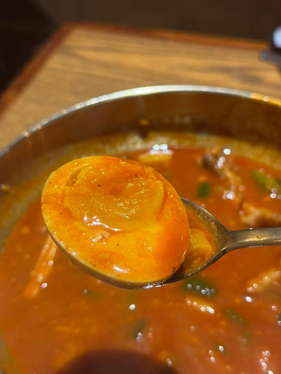 The soft-boiled egg inside the soupy dakbal