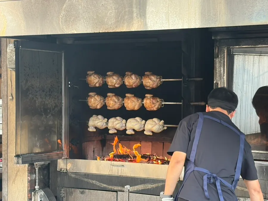 Chicken smoking and turning on the wood-fired grill