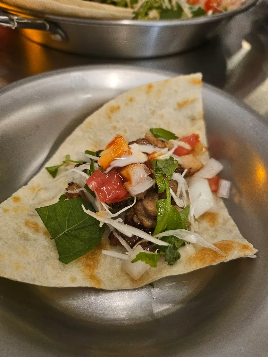 A tortilla topped with meat and vegetables